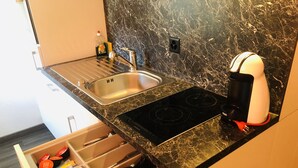 A kitchen with a black marble countertop, stainless steel sink, and a built-in stove. - INSIDE FIVE City Apartments (Zürich)