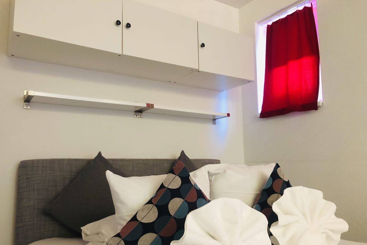 A bed with a grey headboard, white bedding, and multiple pillows including a polka dot one.