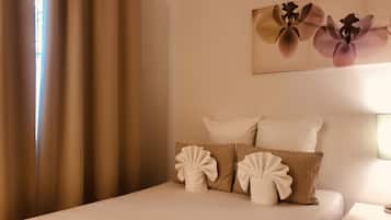 Une chambre d’hôtel avec un lit, des oreillers, une table de chevet et un tableau représentant des fleurs accroché au mur.