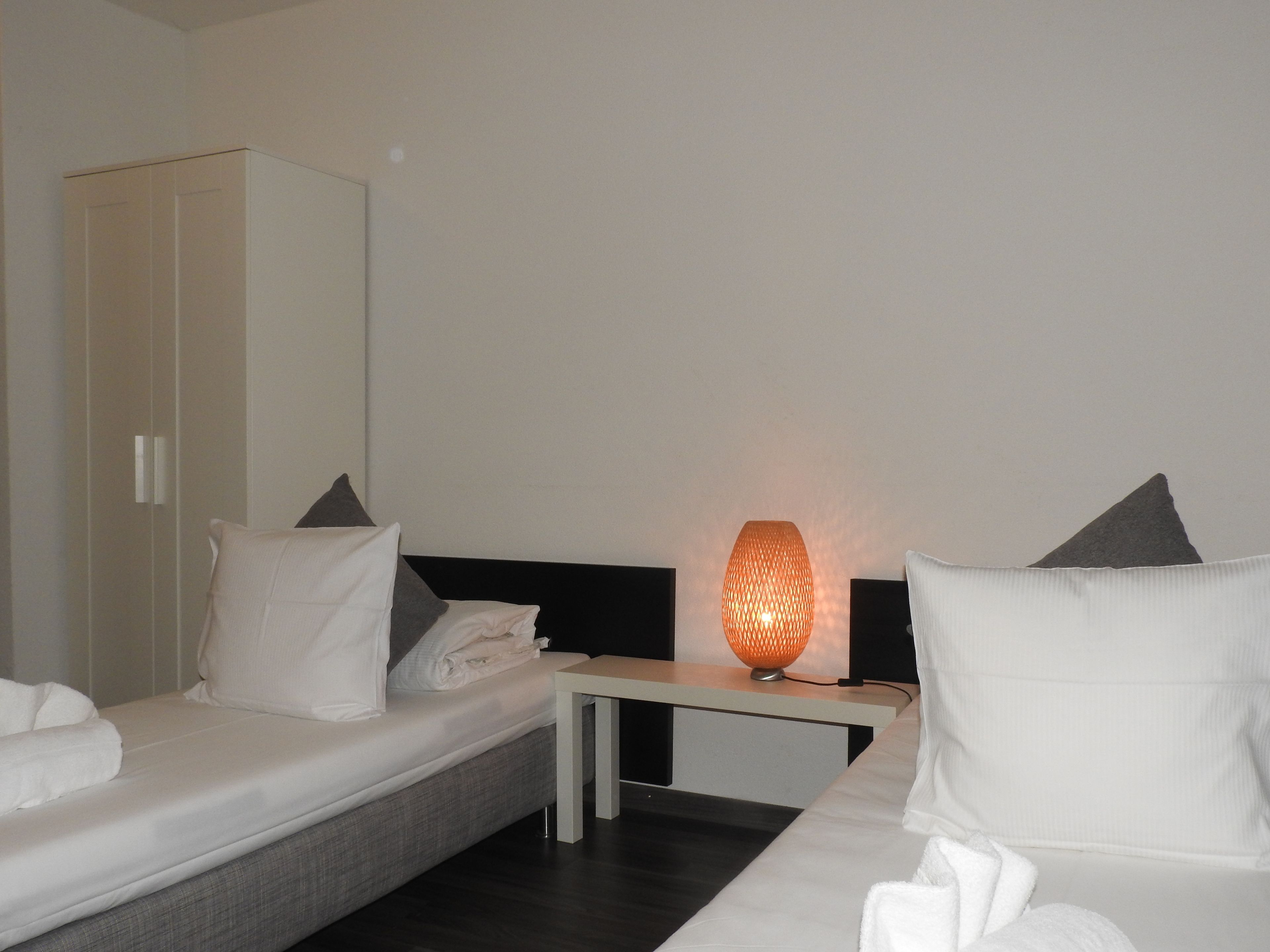 Une chambre d’hôtel comprenant un lit, une table de chevet, une lampe et une armoire.