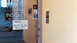 A hotel entrance with a glass door, a Wi-Fi sign, a pull handle, and a security intercom. - INSIDE FIVE City Apartments (Zürich)