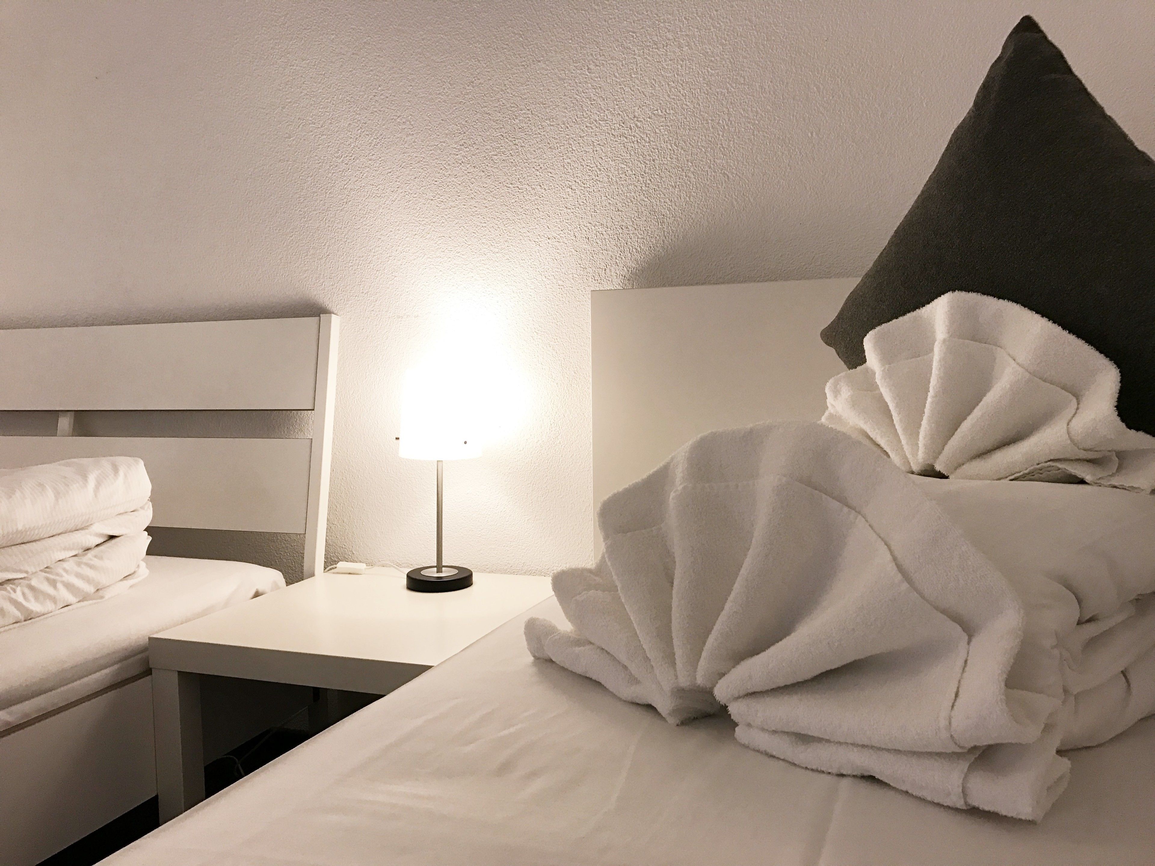 Una habitación de hotel con una cama bien hecha, una mesita de noche con una lámpara y un cabecero.