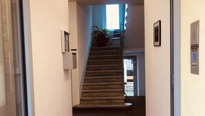 A hallway with a red carpet leading to a staircase, a potted plant, and a framed picture on the wall. - INSIDE FIVE City Apartments (Zürich)
