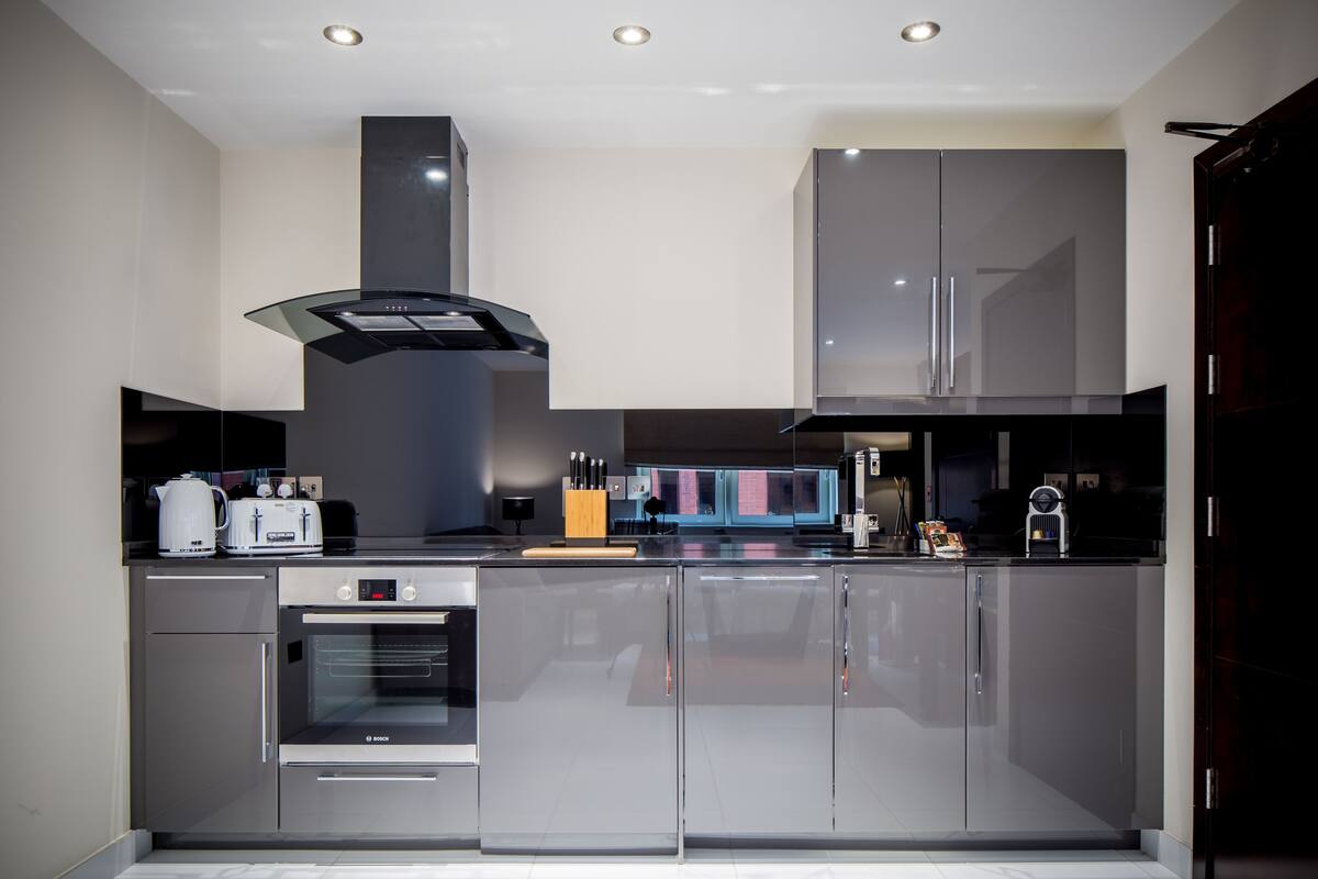 A modern kitchen with stainless steel appliances, a built-in oven, and a large island with a cutting board.