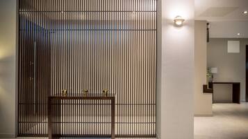 A modern interior with a wooden table and a vertical slat partition.