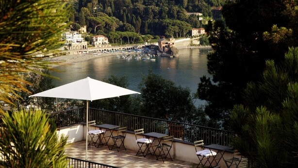 A terrace with outdoor seating overlooking a lake, surrounded by trees and buildings. - La Madonetta - Dimora d'epoca - (Levanto)