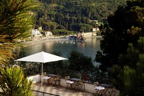 A terrace with outdoor seating overlooking a lake, surrounded by trees and buildings. - La Madonetta - Dimora d'epoca - (Levanto)