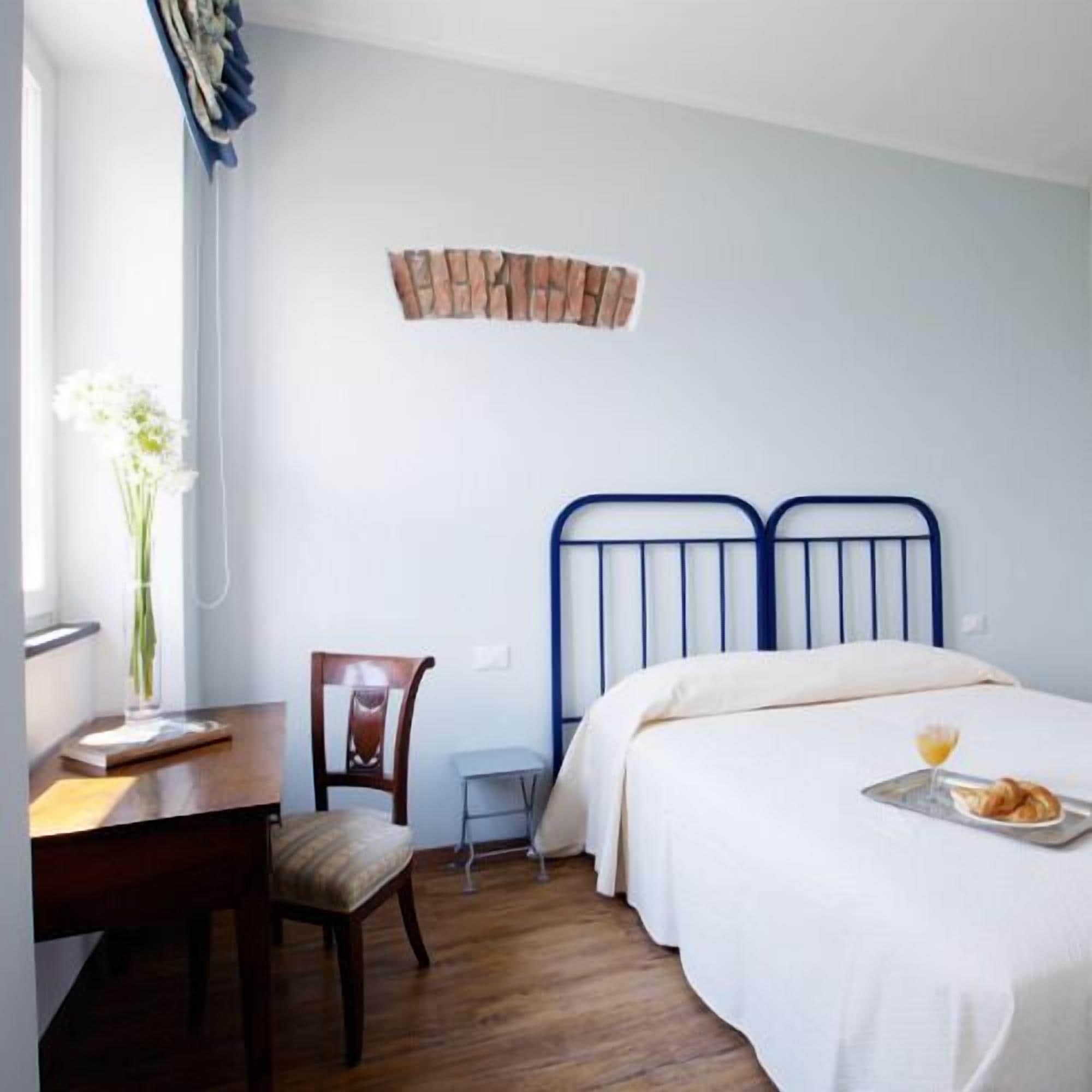 A bedroom with a bed, a chair, a desk, and a window with curtains.