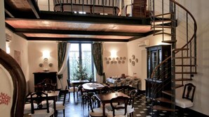 A multi-level dining area with a checkered floor, a spiral staircase, and a view of the outdoors through large windows. - La Madonetta - Dimora d'epoca - (Levanto)