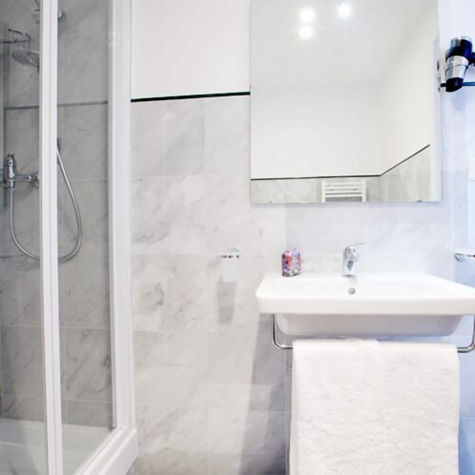 Un bagno con box doccia in vetro, un lavandino bianco con un asciugamano e uno specchio sopra il lavandino.