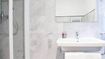 Un bagno con box doccia in vetro, un lavandino bianco con un asciugamano e uno specchio sopra il lavandino.