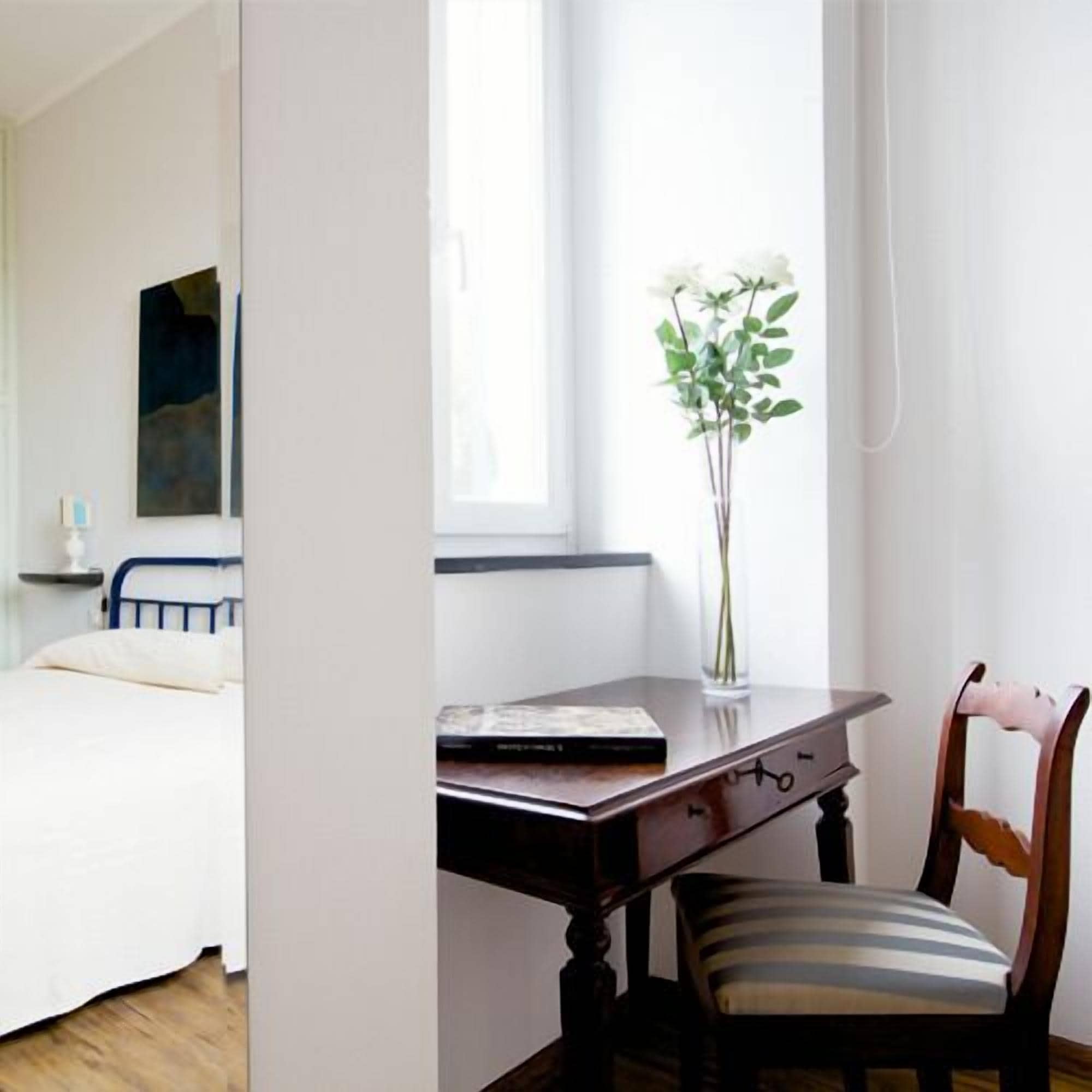 Ein Schlafzimmer mit einem Bett, einem Schreibtisch mit Stuhl, einem Fenster mit Blick und einem Bild an der Wand.