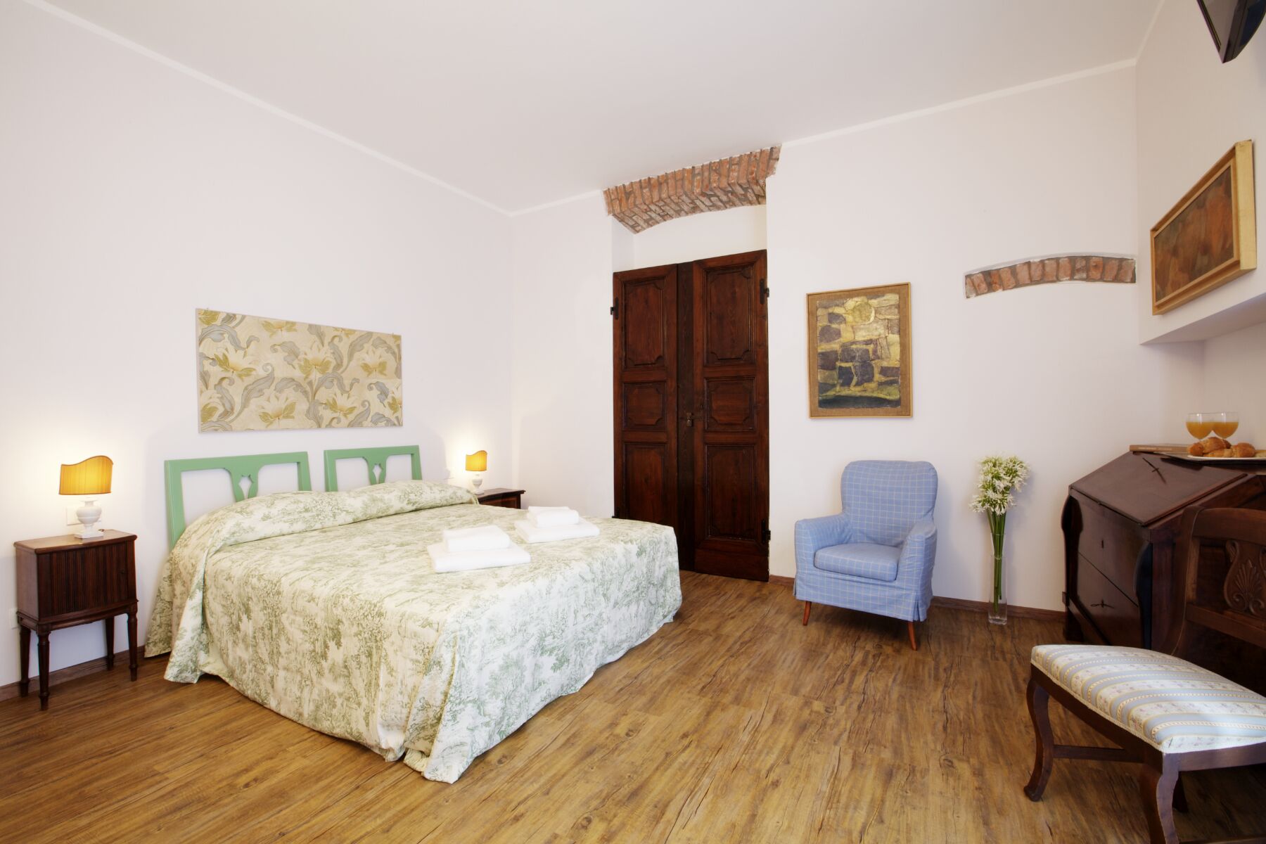 Ein Schlafzimmer mit einem Bett, einem Sessel, einem Schreibtisch und einem Kleiderschrank.