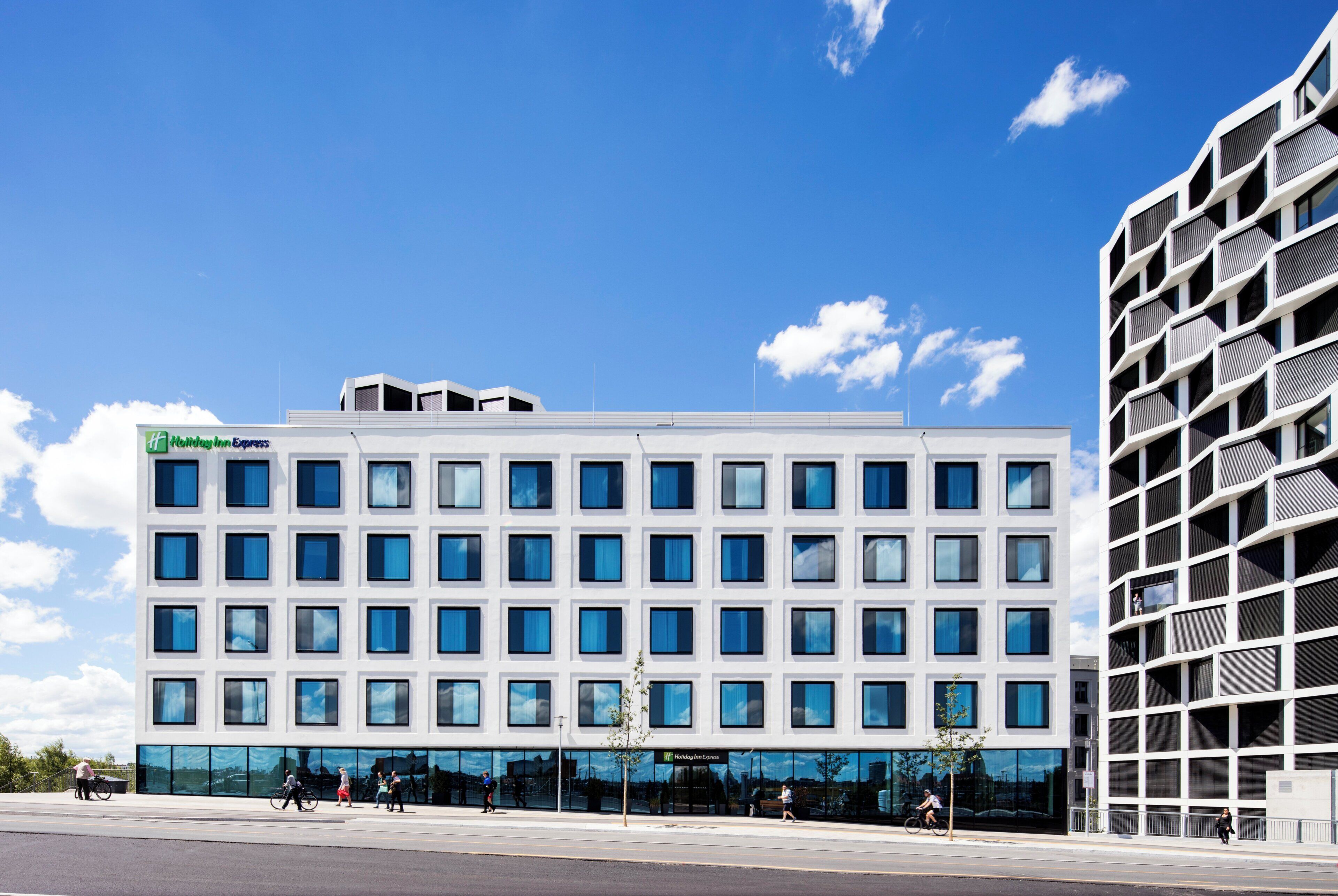 Ein modernes Hotelgebäude mit flacher Fassade, großen Fenstern und einem sichtbaren Schild für Holiday Inn Express.