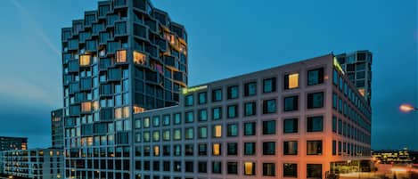 Un hotel moderno con un diseño arquitectónico único, que cuenta con varios balcones y un llamativo letrero Holiday Inn Express.