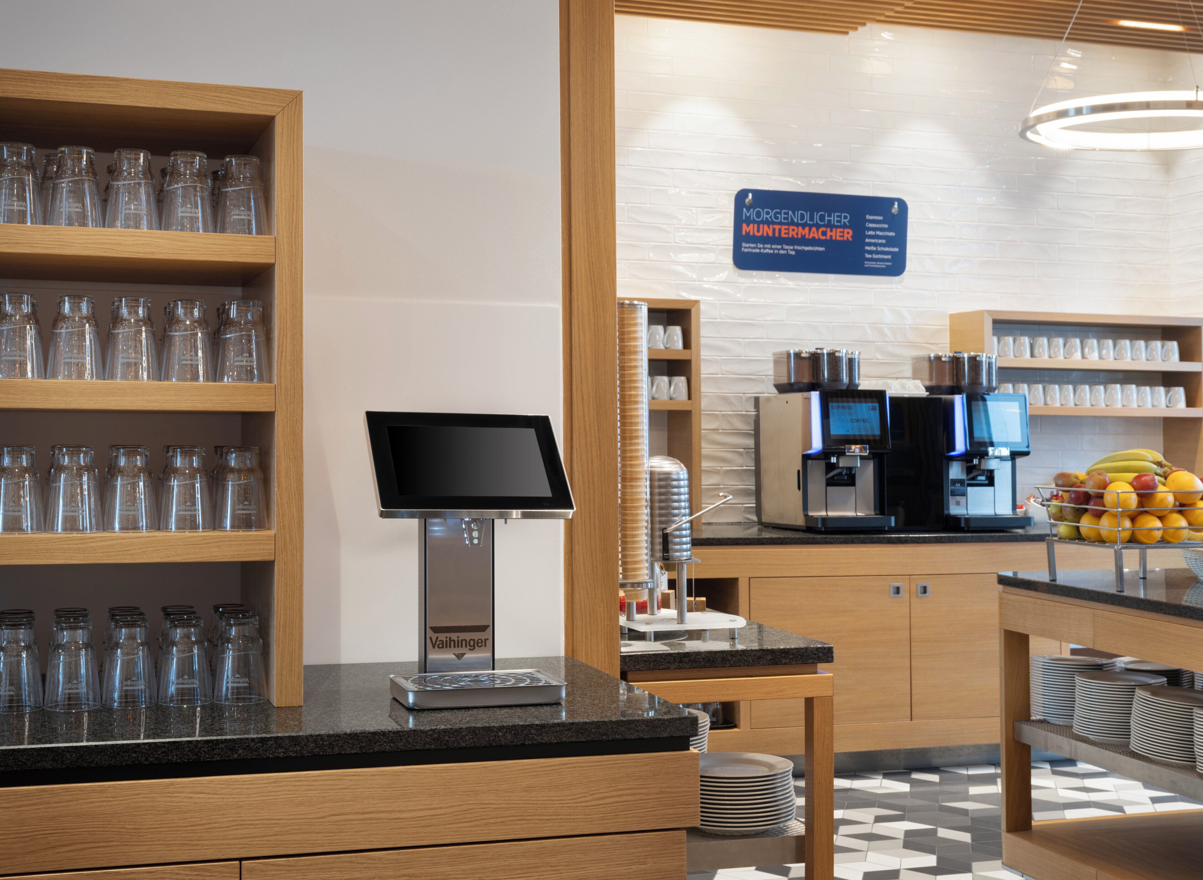L’intérieur d’un café moderne, avec un espace dédié aux commandes numériques, des machines à café et un pr ésentoir de fruits.