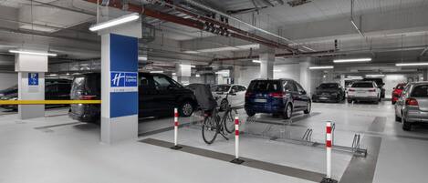 A multi-level parking garage with several cars parked, including a black SUV and a blue minivan.