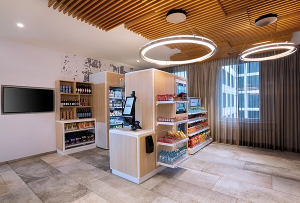 Un espace de vente moderne, doté d’étagères en bois, d’un kiosque numérique et d’une grande fenêtre agrémentée de rideaux.