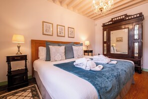 A neatly made bed with a blue blanket and white linens, two bedside lamps, a wooden nightstand, and a large mirror. - Tradicampo Eco Country Houses (Nordeste)