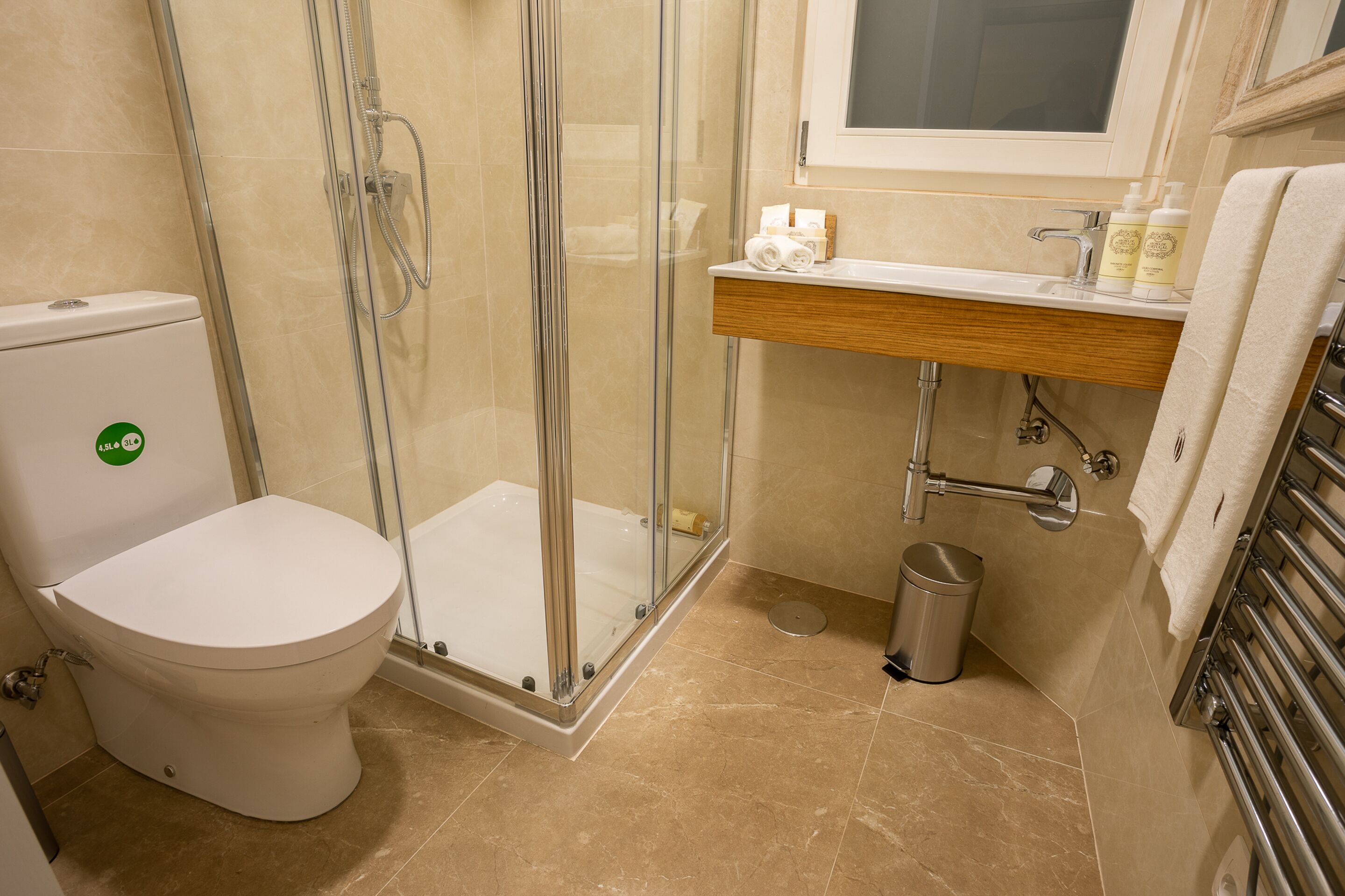 Une salle de bain comprenant des toilettes, une douche en verre, un lavabo avec des articles de toilette et un porte-serviettes.