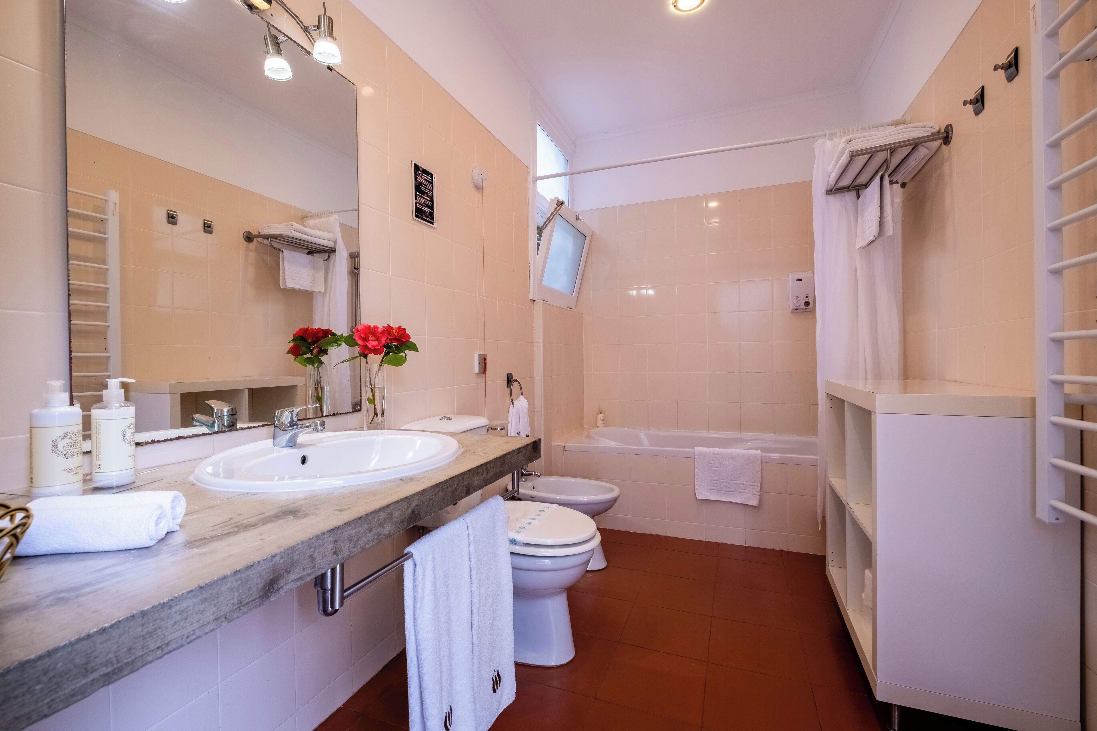 Een moderne badkamer met een wastafel, toilet en bad. Handdoeken en toiletartikelen liggen op het aanrecht.