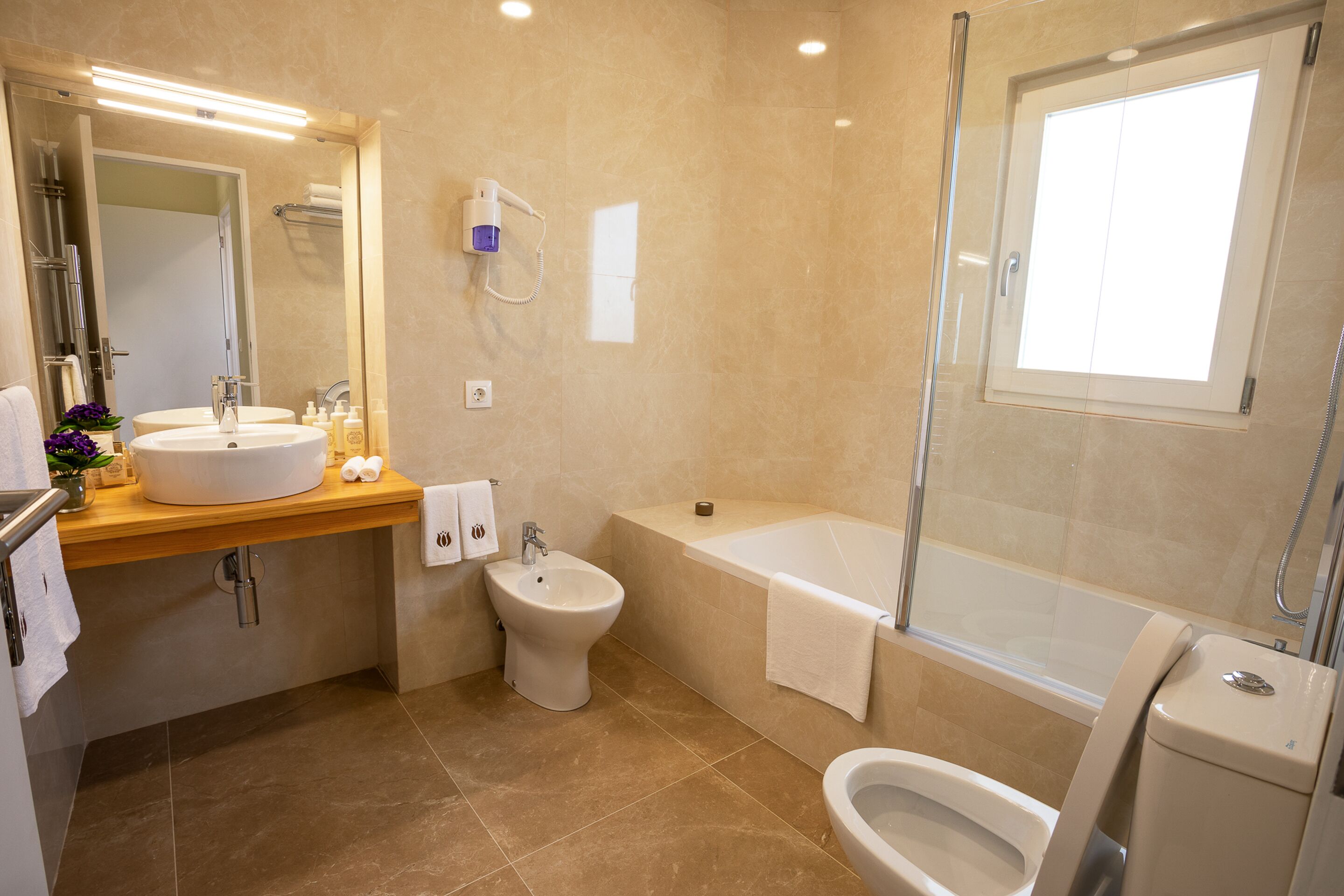 A modern bathroom with a sink, bidet, toilet, and bathtub.