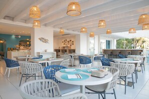 A spacious restaurant with round tables, blue and white chairs, and hanging wicker lamps. - Hotel Blumarea, BW Signature Collection (Castelsardo)