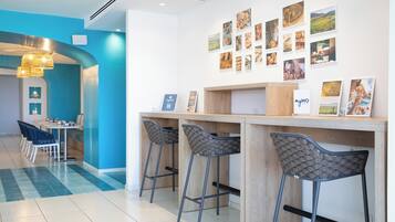 Un'area bar moderna con sgabelli alti, un bancone in legno e una parete decorata con quadri.