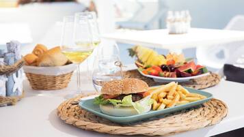 A table with a burger, fries, and a fruit salad.