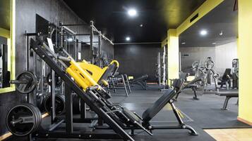 Un gimnasio con equipo de ejercicio variado, que incluye máquinas de pesas y pesas libres.