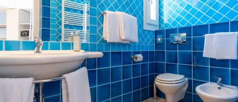 Ein Badezimmer mit Waschbecken, Toilette, Bidet und blauen Fliesenwänden.