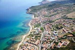 An aerial view of a coastal town with a beach, residential buildings, and a mix of paved and unpaved roads. - Hotel Blumarea, BW Signature Collection (Castelsardo)
