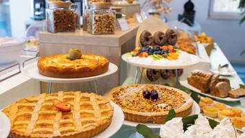 Un bufé con diversos postres, como tartas, pasteles y repostería.
