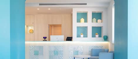 Un espace d’accueil moderne avec un comptoir blanc, des carreaux aux motifs bleus et blancs, et une palette de couleurs bleue et blanche.