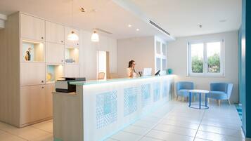 A modern reception area with a light-colored counter, blue chairs, and a large window providing natural light.