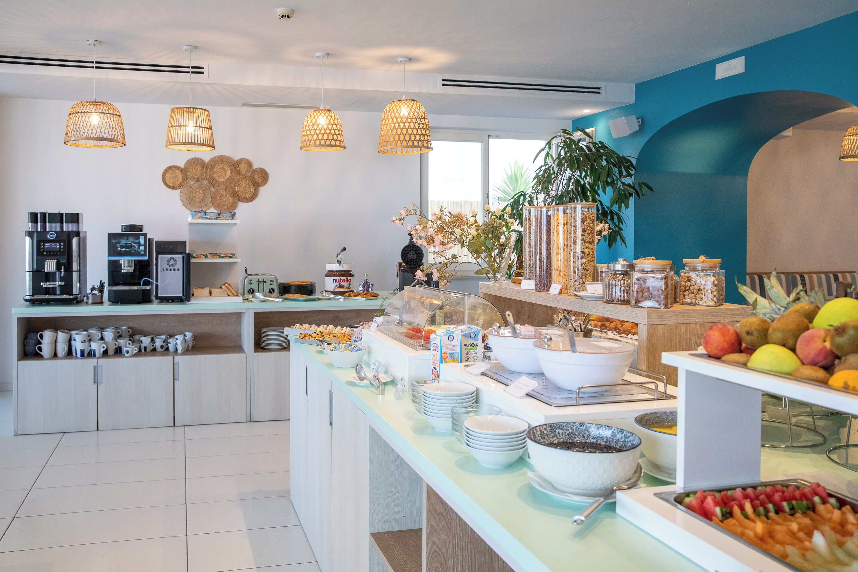 Een moderne ontbijtbar met diverse eet- en drinkmogelijkheden, zoals fruit, ontbijtgranen en koffieautomaten.