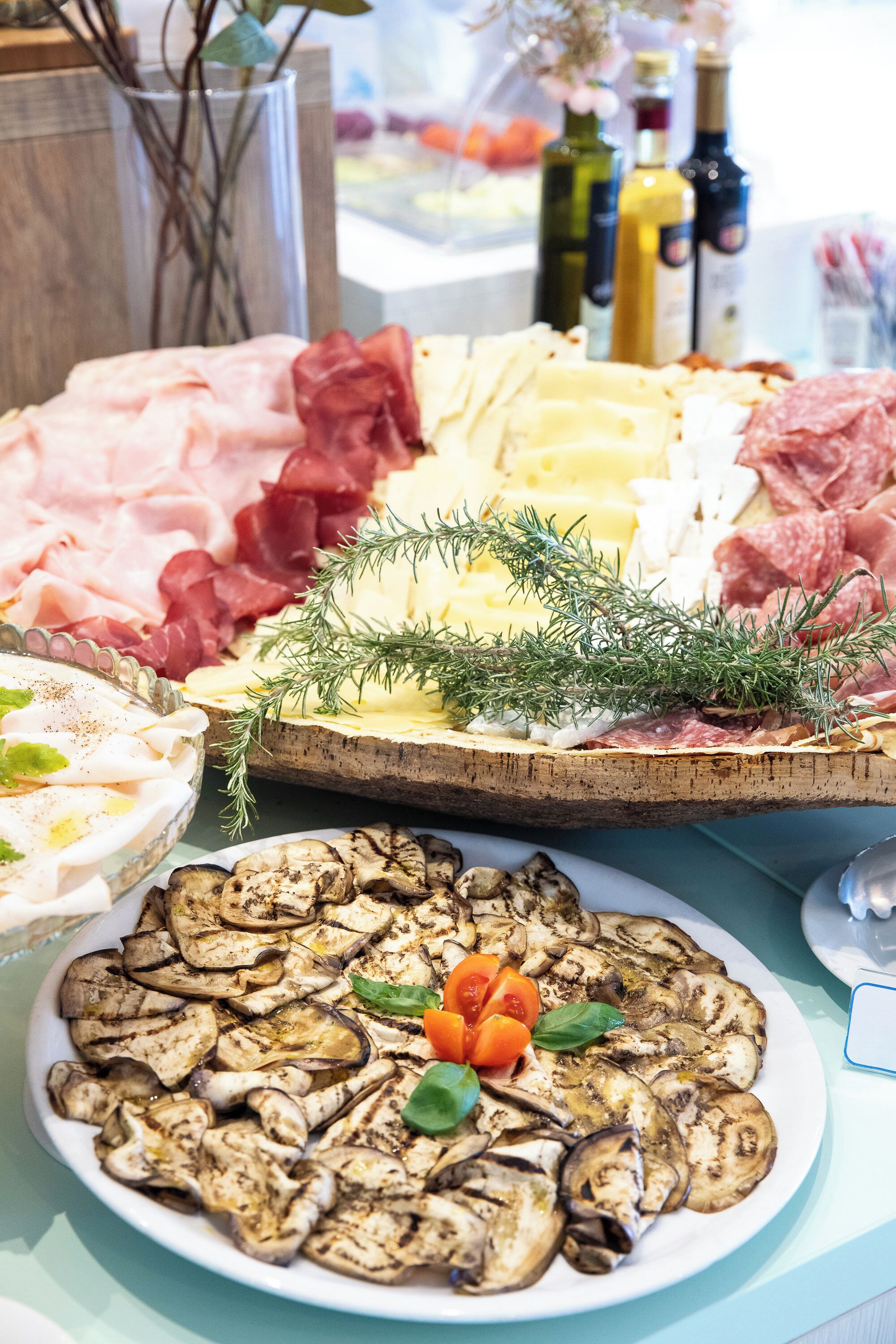 A charcuterie board with various meats, cheeses, and grilled vegetables.