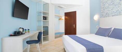 A hotel room with a bed, a desk, a chair, a TV, and a wardrobe.