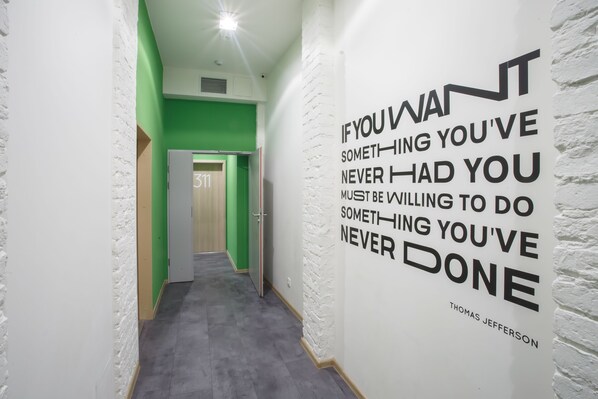 Un pasillo con una cita motivacional en la pared, una puerta con la etiqueta “311” y una decoración en tonos verde y blanco.