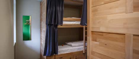 Habitación con literas, paredes de madera y una puerta verde.