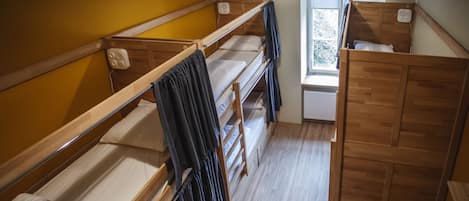 A dormitory room with bunk beds, a window with a view, and a radiator.