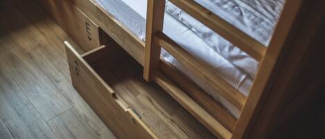 A wooden bunk bed with a lower bunk drawer.