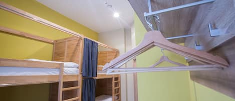 Une chambre avec des lits superposés en bois, une armoire et un portant à vêtements.