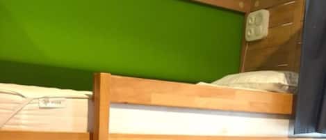 Una cama litera con estructura de madera y pared verde.
