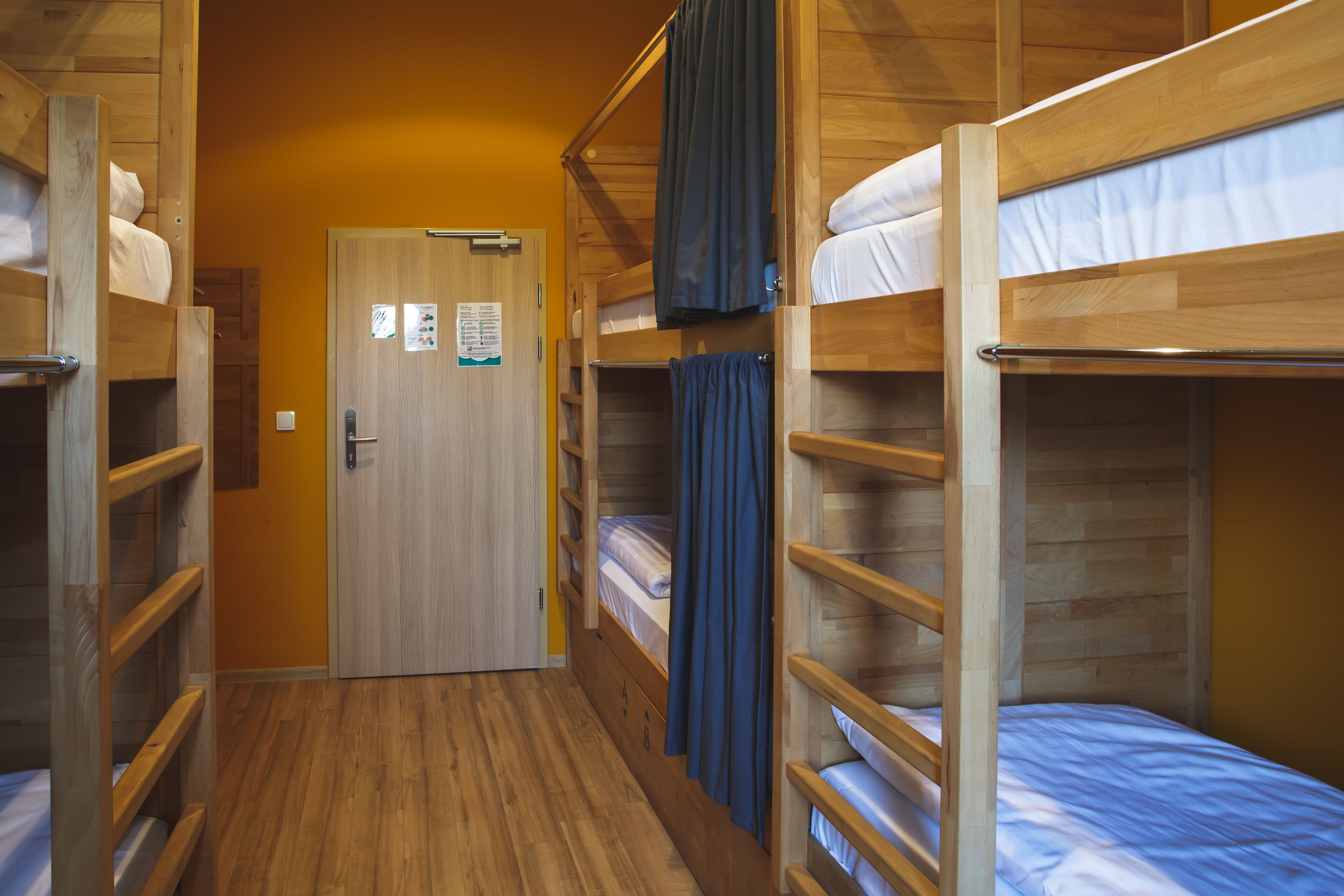 Un couloir avec des lits superposés, un plancher en bois et une porte sur laquelle est apposée une pancarte.