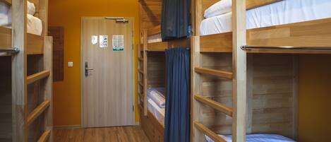 Un couloir avec des lits superposés, un plancher en bois et une porte sur laquelle est apposée une pancarte.