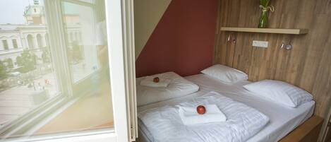 A room with a bed, a window, and a wooden wall.
