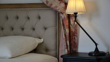 A bedroom with a tufted headboard, a bedside lamp, and a nightstand.