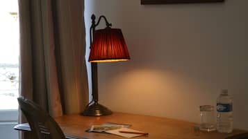 Une table en bois, une lampe, une chaise, une bouteille d’eau et un verre.