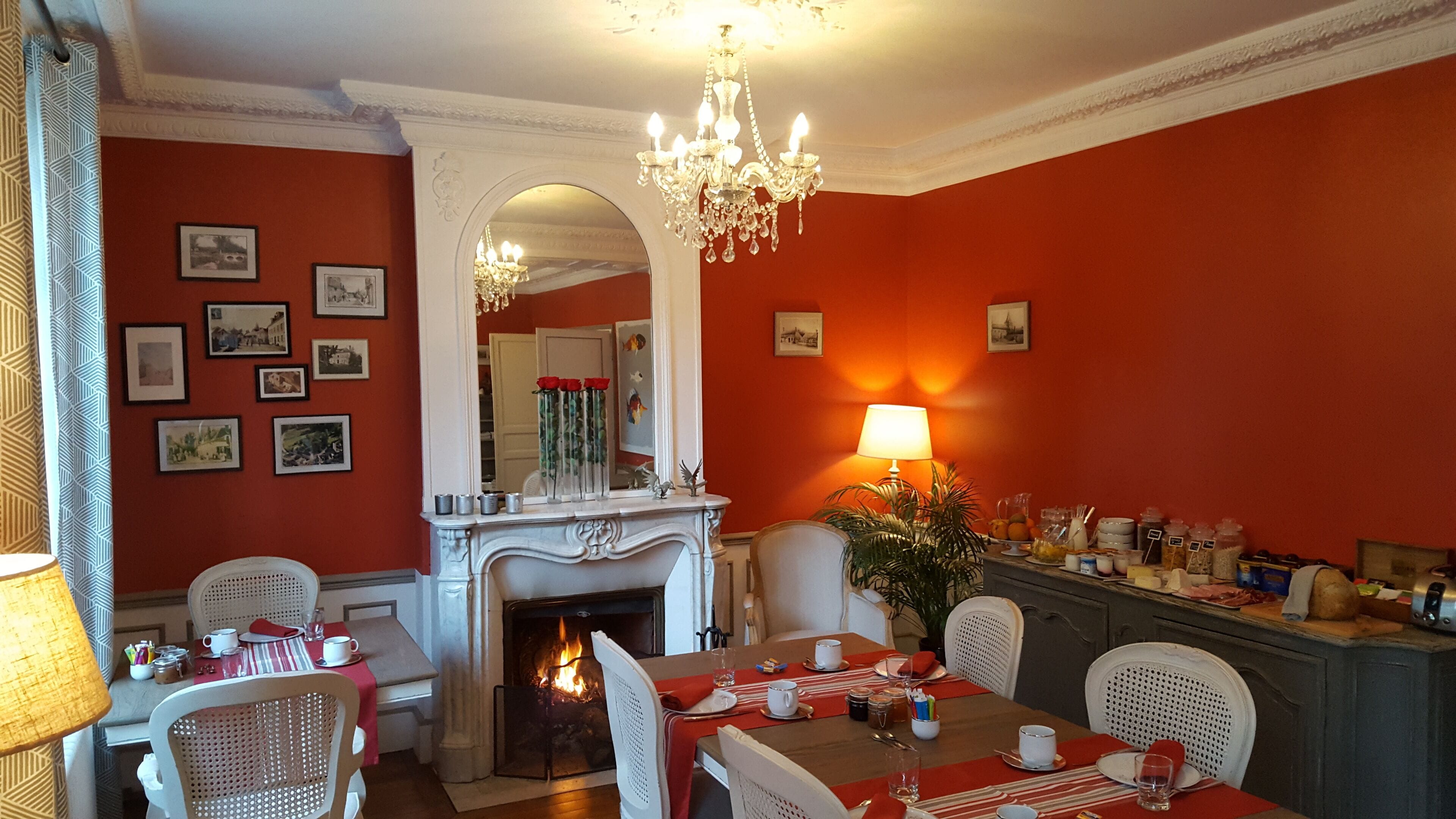 A dining room with a fireplace, a chandelier, and a table set for four.